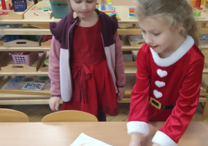 Dziewczynka kładzie list do Mikołaja na stole.