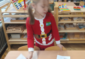 Dziewczynka kładzie list do Mikołaja na stole.