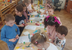 dzieci przy długim stole projektujące sweterki