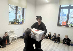 Przekazujemy seniorką świąteczną paczkę ( herbatki, kawę i ciasteczka) przyniesione przez dzieci