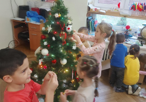 dzieci zawieszają ozdoby na drzewku