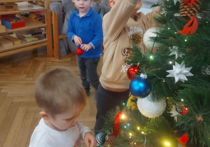 dzieci zawieszają ozdoby na drzewku