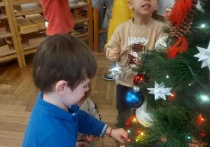 dzieci zawieszają ozdoby na drzewku