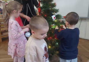 dzieci zawieszają ozdoby na drzewku