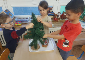 dzieci zawieszają ozdoby na drzewku