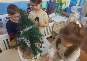 dzieci zawieszają ozdoby na drzewku
