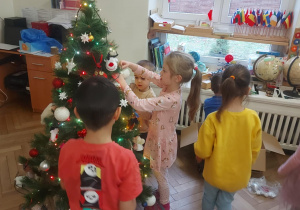 dzieci zawieszają ozdoby na drzewku