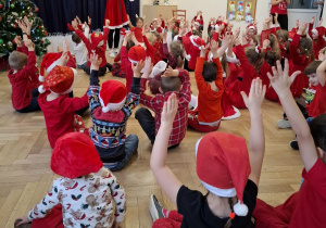 kobieta w stroju Mikołajki pokazuje co mają robić dzieci. Dzieci trzymają ręcę w górze
