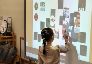 dziewczynka układa świąteczne miasteczko z puzzli