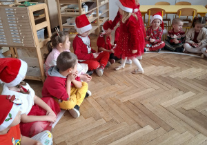 dwie dziewczynki wręczają prezenty dzieciom siedzącym na elipsie