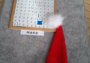 tablica do 100, obok leży czapka Mikołaja. Maks