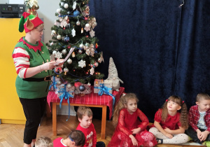 Nauczyciel czyta list, a dzieci siedzą w kole.