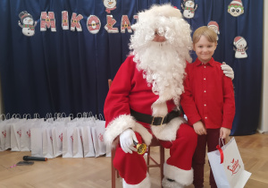 Chłopiec stoi obok Mikołaja.