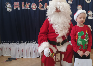 Chłopiec stoi obok Mikołaja.