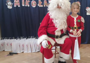 Dziewczynka stoi koło Mikołaja.