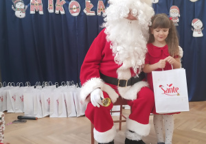 Dziewczynka stoi koło Mikołaja.