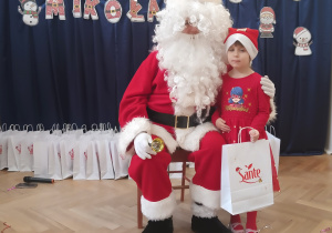 Dziewczynka stoi koło Mikołaja.