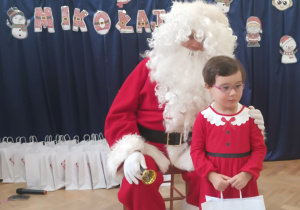 Dziewczynka stoi koło Mikołaja.