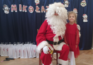 Dziewczynka stoi koło Mikołaja.