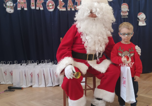 Chłopiec stoi koło Mikołaja.