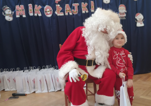 Chłopiec stoi koło Mikołaja.