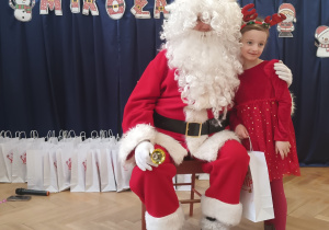 Dziewczynka stoi koło Mikołaja.