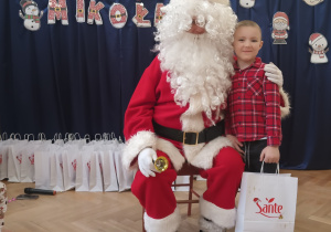 Chłopiec stoi koło Mikołaja.