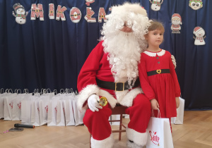 Dziewczynka stoi koło Mikołaja.