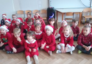 Dzieci siedzą na podłodze.