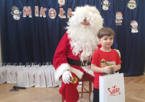 Chłopiec stoi koło Mikołaja.