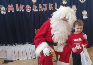 Chłopiec stoi koło Mikołaja.
