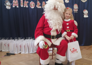 Dziewczynka stoi koło Mikołaja.