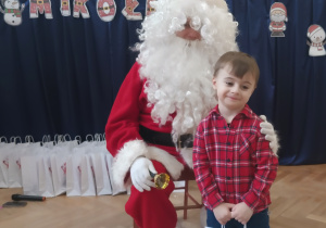 Chłopiec stoi koło Mikołaja.