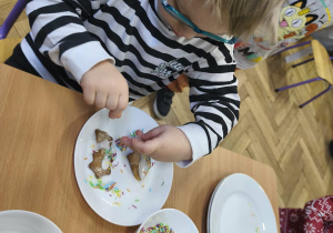 Na zdjęciu widzimy chłopca, który dekoruje kolorową posypką pierniczki.