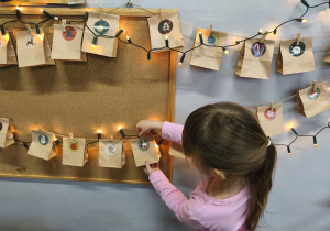 Na zdjęciu widzimy dziewczynkę, która sięga po kolejną torebkę z kalendarza adwentowego.