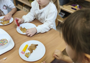 Na zdjęciu widzimy dziewczynki, które dekorują pisakami i posypkami pierniczki.