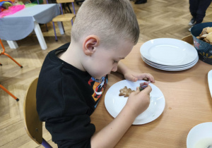 Na zdjęciu widzimy chłopca, który dekoruje pisakami i posypkami pierniczki.