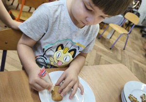 Na zdjęciu widzimy chłopca, który dekoruje pisakami i posypkami pierniczki.