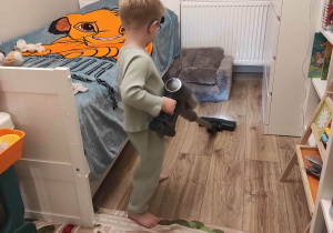 Na zdjęciu widzimy chłopca, który porządkuje swój pokój.