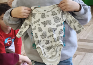 Chłopiec pokazuje ubranko z okresy niemowlęctwa