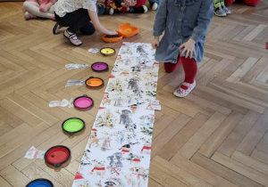 Dzieci wykonują świąteczne zadanie dobierając pieski z prezentami do miseczek