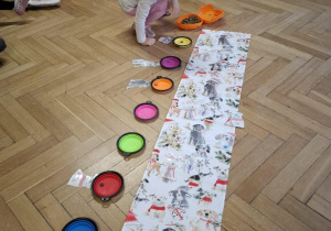 Dzieci wykonują świąteczne zadanie dobierając pieski z prezentami do miseczek