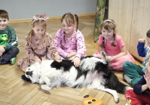 Dzieci delikatnie głaszczą psa, przestrzegając zasady zajęć