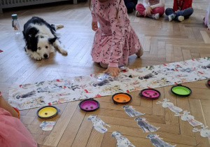 Dzieci wykonują świąteczne zadanie dobierając pieski z prezentami do miseczek