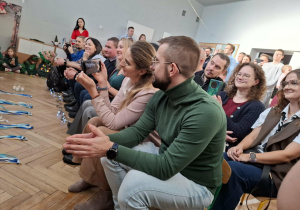 Rodzice siedzący na krzesełkach, oglądający występ