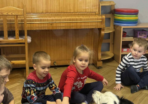 Zdjęcie przedstawia dzieci głaszczące psa.