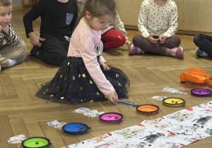 Zdjęcie przedstawia dziewczynkę układającą postać psa pod podstawkiem.