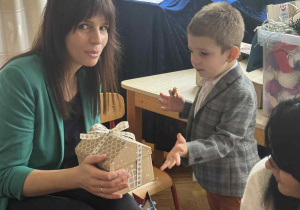 Zdjęcie przedstawia kobietę i chłopca. Kobieta trzyma w ręku prezent.