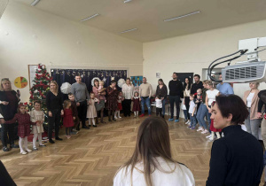 Zdjęcie przedstawia rodziców i dzieci, wspólnie stojących w kole.