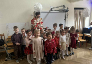 Zdjęcie przedstawia dzieci z kobietą, przebraną za choinkę.